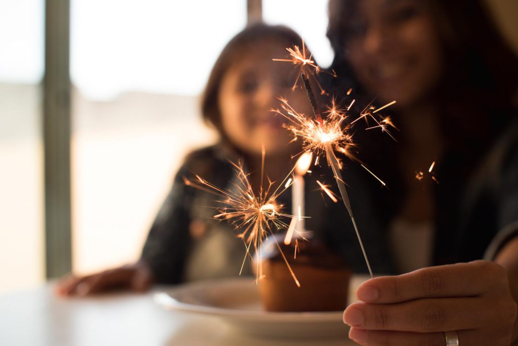 A girl is holding a sparkler on a plate.