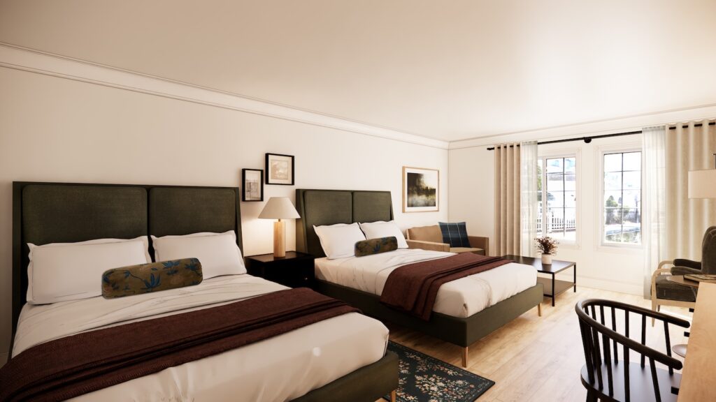 A hotel room with two double beds, white walls, framed artwork, a desk, a sofa, and large windows with curtains letting in natural light.