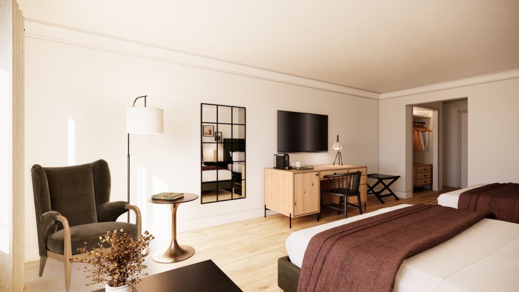 Modern hotel room with two beds, a large wall-mounted TV, desk, armchair, floor lamp, and mirror. Neutral decor with natural light coming from a window on the left.